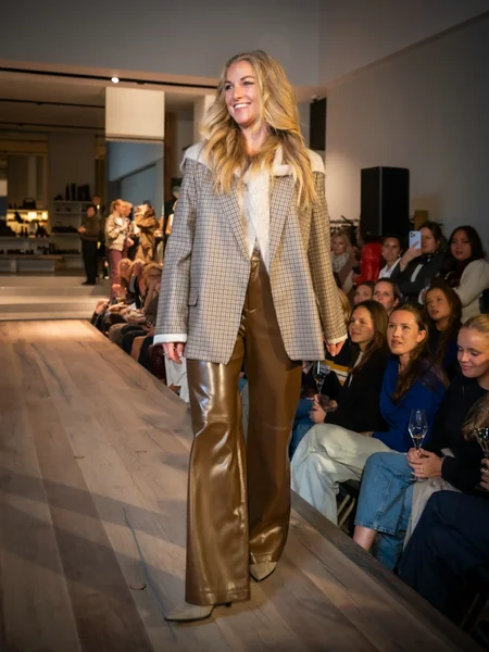 Geruite blazer met cognackleurige leren broek en een grijs laarsje