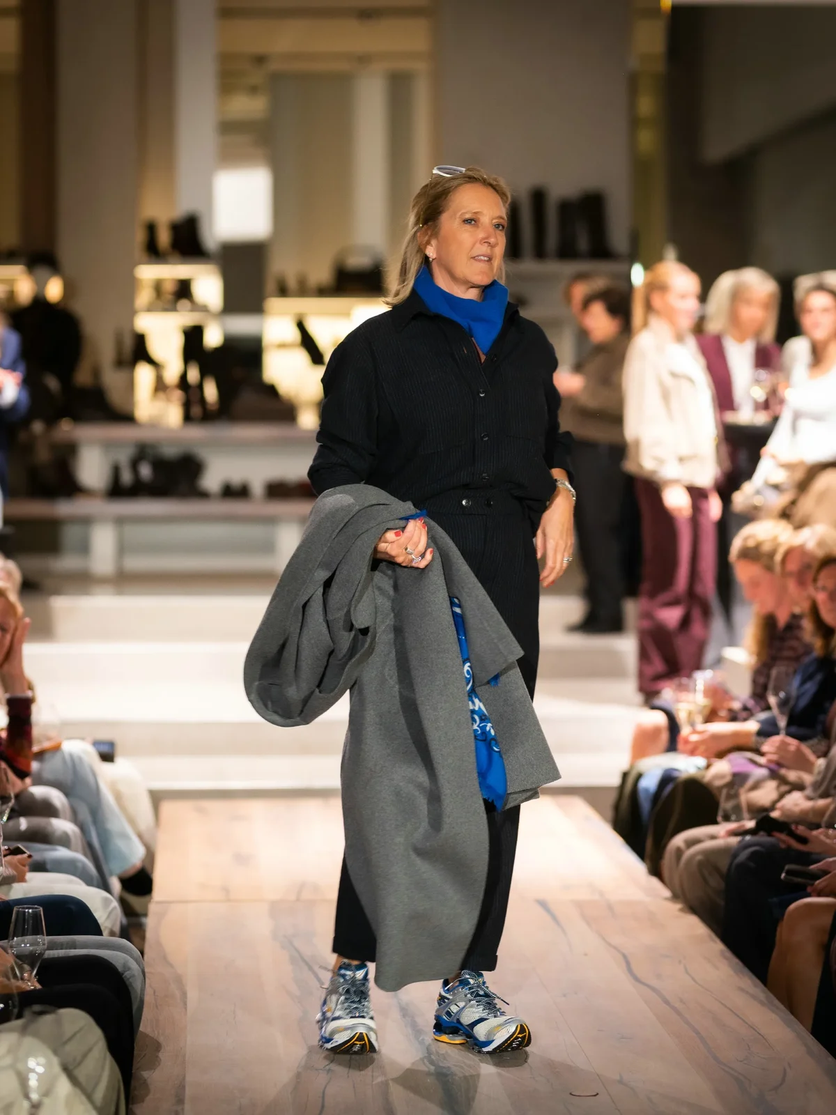 Grijze jas met blauwe blouse, broek en sneakers